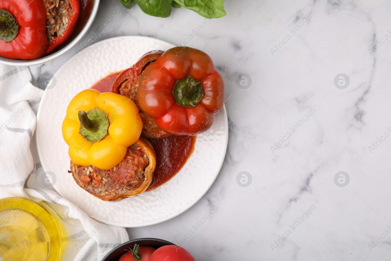 Photo of Delicious stuffed bell peppers served on white marble table, flat lay. Space for text