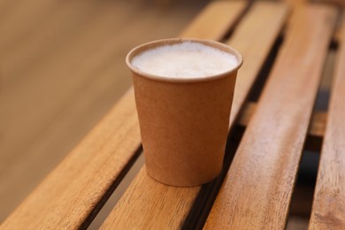 Takeaway paper cup with coffee on wooden table, closeup