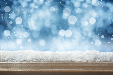 Image of Wooden surface with snow against blue background, bokeh effect