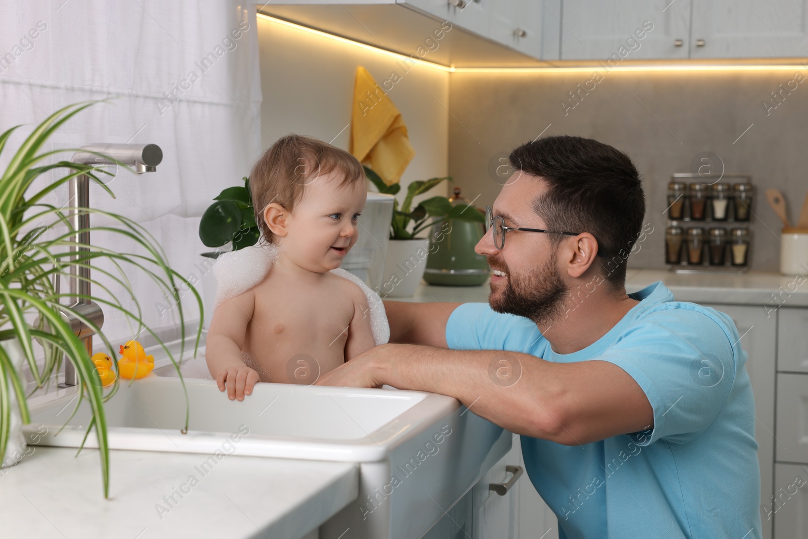 Photo of Father washing his little baby in sink at home