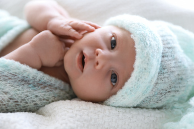 Photo of Cute newborn baby in warm hat lying on white plaid, closeup