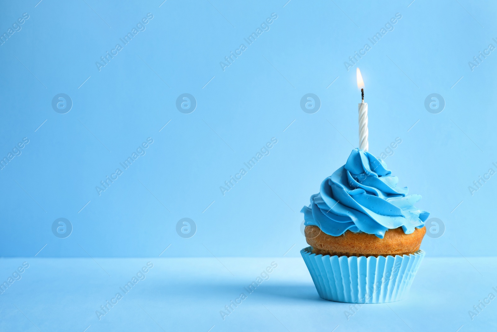 Photo of Delicious birthday cupcake with candle on color background