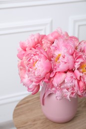 Beautiful bouquet of pink peonies in vase on wooden table indoors