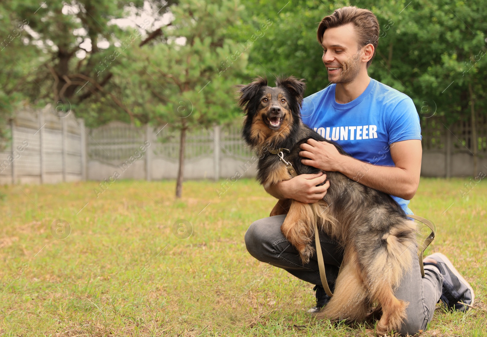 Photo of Male volunteer with homeless dog at animal shelter outdoors