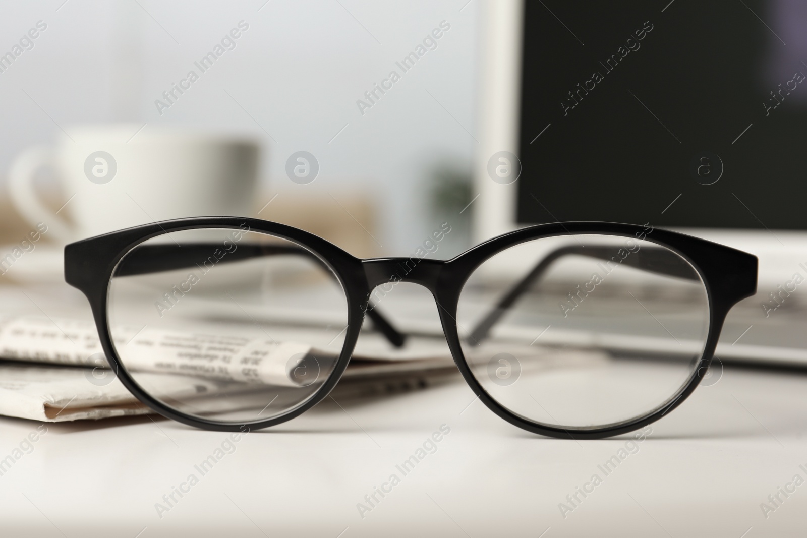 Photo of Newspapers and glasses on white table indoors, closeup