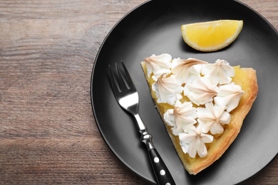 Photo of Piece of delicious lemon meringue pie served on wooden table, flat lay. Space for text