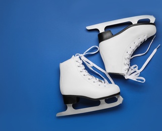 Photo of Pair of figure ice skates on blue background, flat lay. Space for text