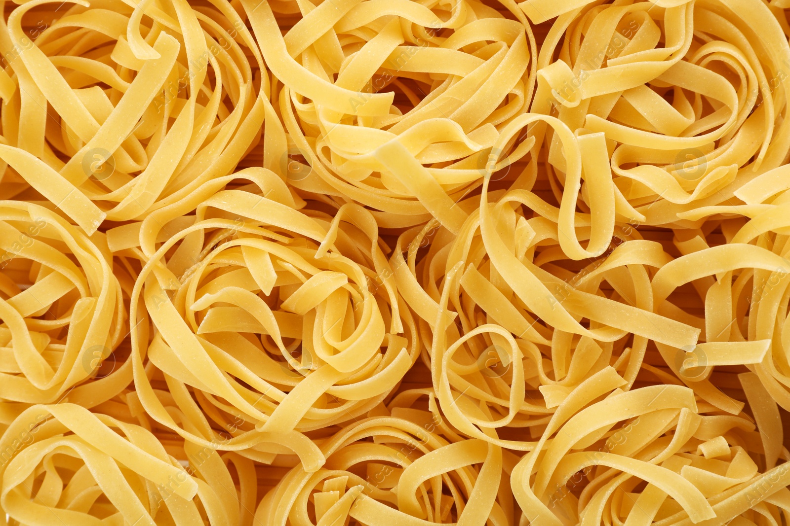 Photo of Uncooked fettuccine pasta as background, closeup