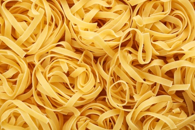Uncooked fettuccine pasta as background, closeup
