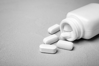 Photo of Container with pills on grey background