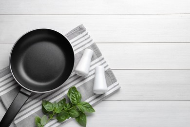 Flat lay composition with frying pan and fresh products on white wooden table, space for text