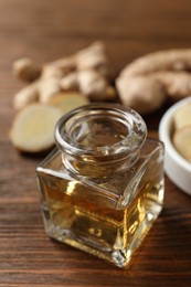 Photo of Ginger essential oil in bottle on wooden table, closeup