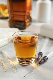 Alcohol and drug addiction. Whiskey in glass, syringes and cocaine on white table