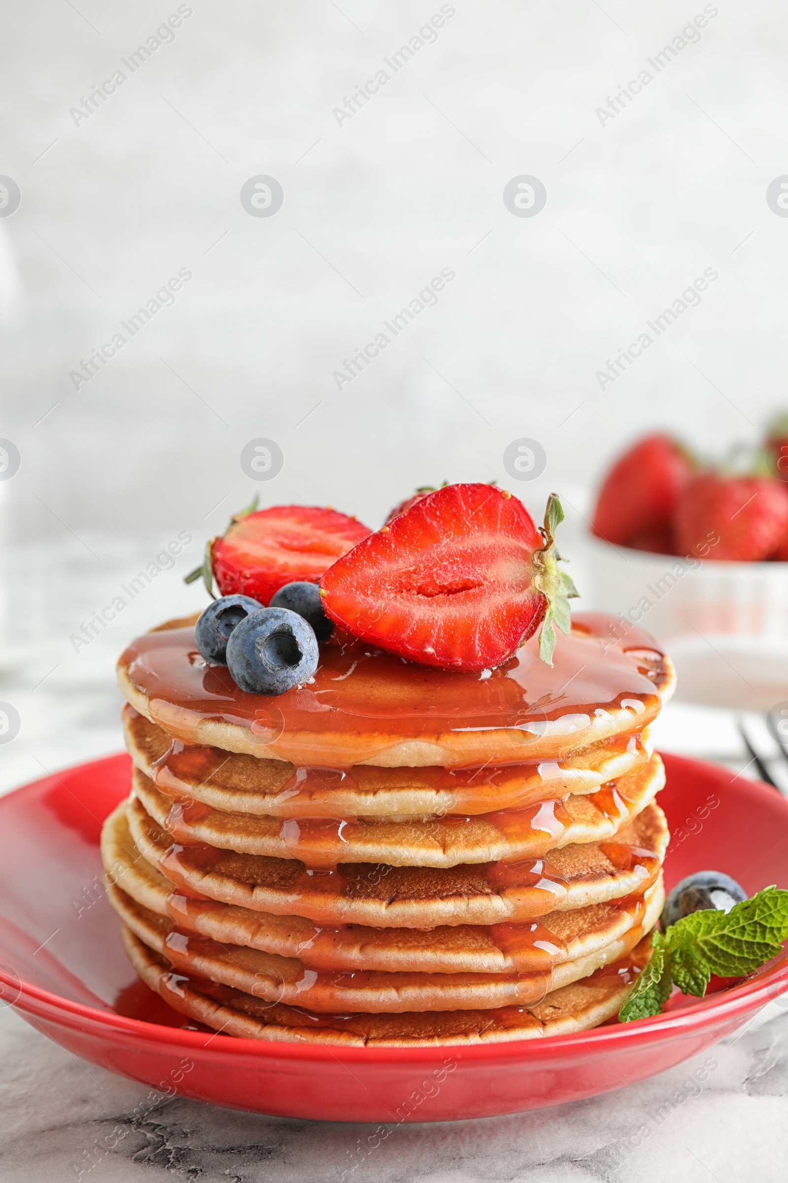 Photo of Plate of delicious pancakes with fresh berries and syrup on white marble table