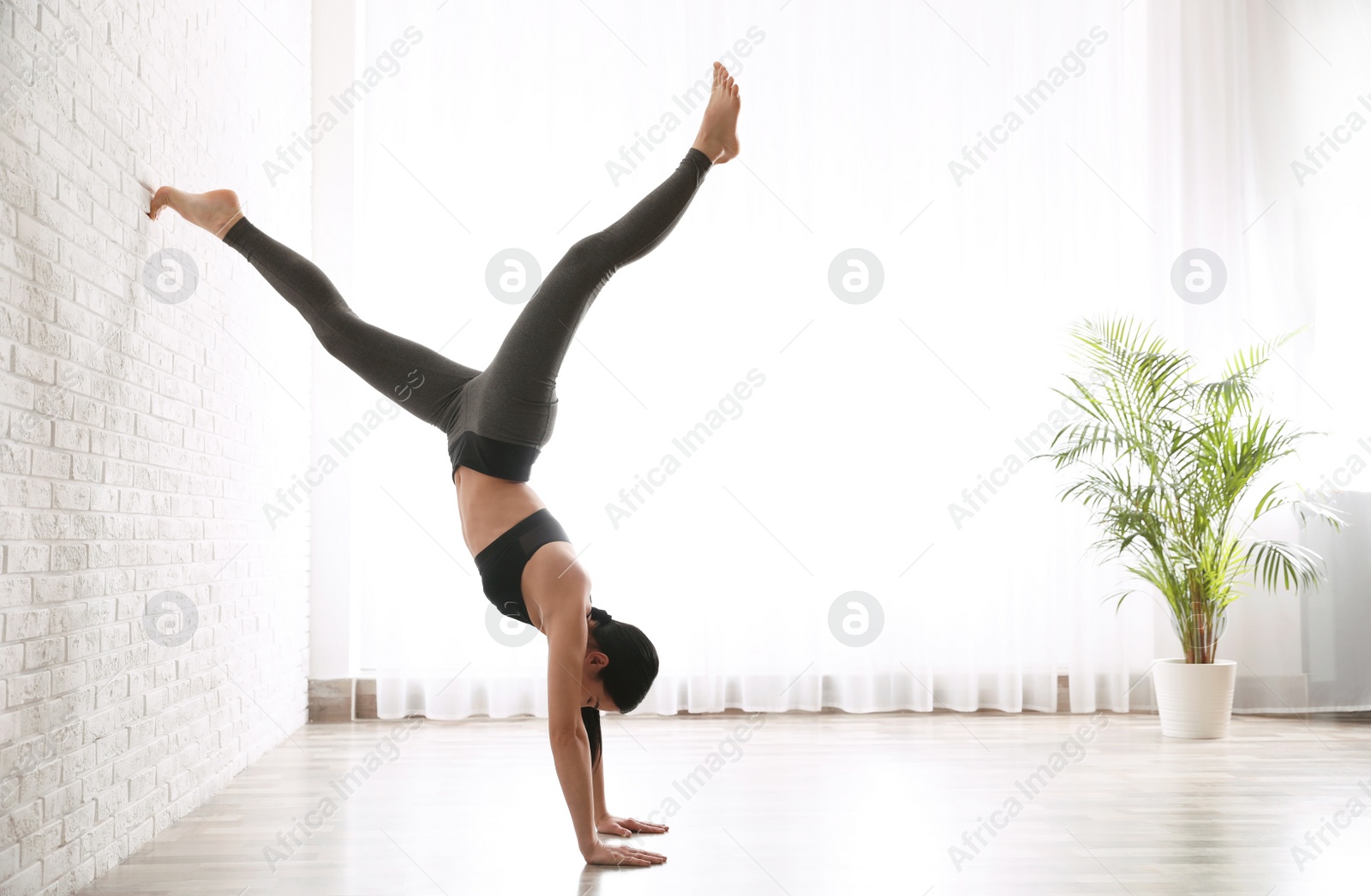 Photo of Young woman practicing downward facing tree asana in yoga studio. Adho Mukha Vrksasana pose