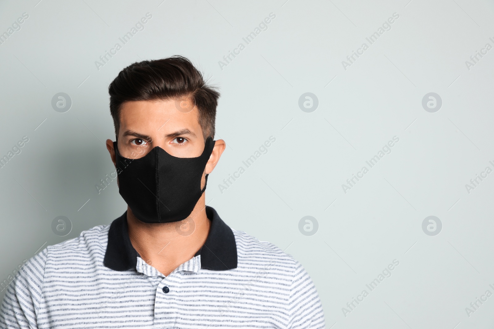 Photo of Man in protective face mask on light grey background. Space for text