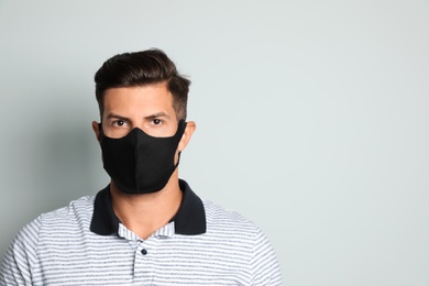 Photo of Man in protective face mask on light grey background. Space for text