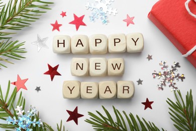 Photo of Happy New Year greeting card. Phrase made with cubes and festive decor on white background, flat lay