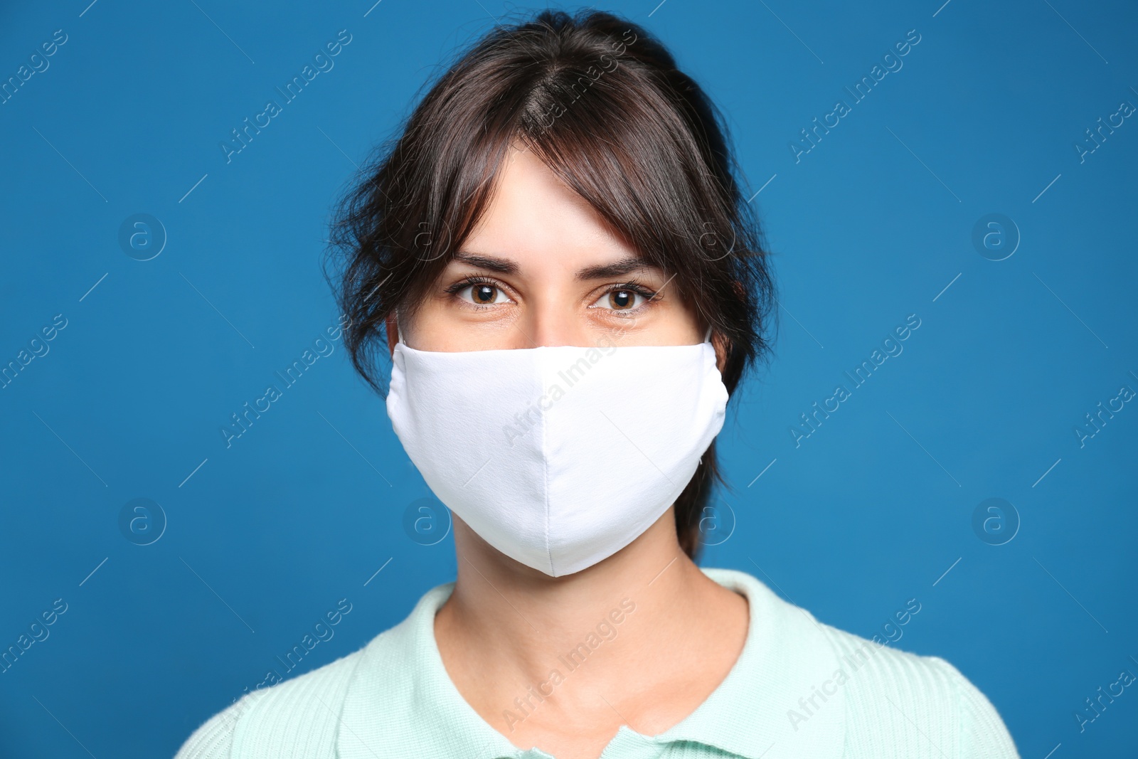 Photo of Young woman in protective face mask on blue background