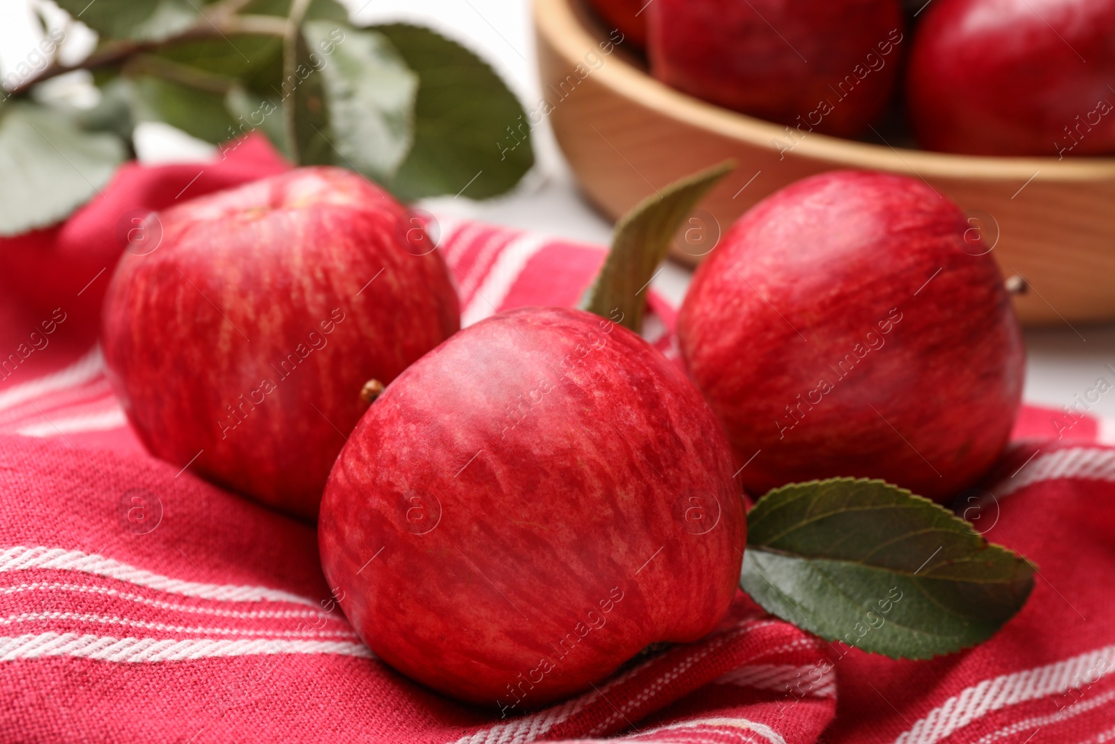 Photo of Fresh red apples with leaves on table, closeup