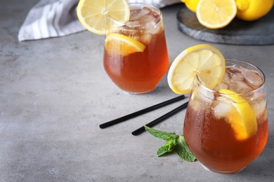 Photo of Delicious iced tea with lemon on grey table. Space for text