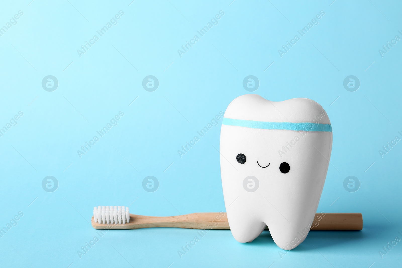 Photo of Model of tooth with happy face, brush and space for text on color background