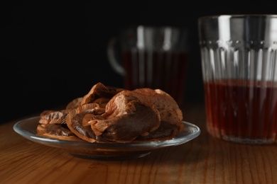 Glass saucer with used tea bags on wooden table