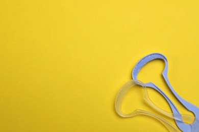 Photo of Tongue cleaners on yellow background, flat lay. Space for text