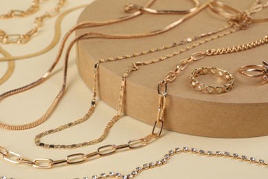 Photo of Metal chains and other different accessories on beige background, closeup. Luxury jewelry