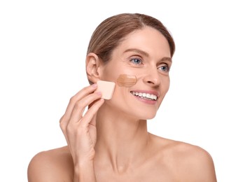 Woman applying foundation on face with makeup sponge against white background