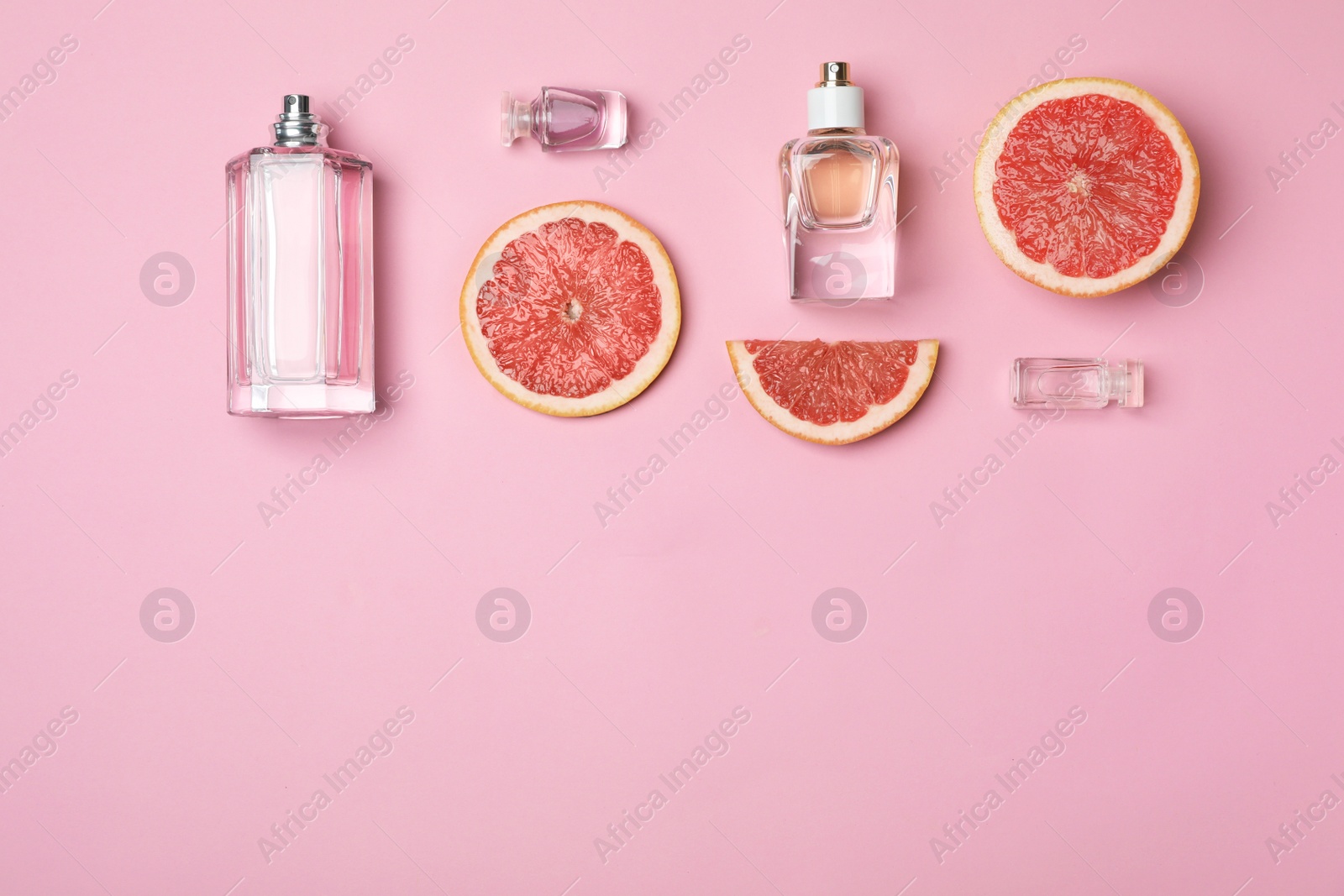 Photo of Bottles of perfume and grapefruit on color background, top view