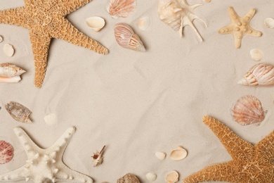 Photo of Frame made of seashells and starfishes on beach sand, top view with space for text