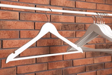 Photo of White clothes hangers on rail near red brick wall