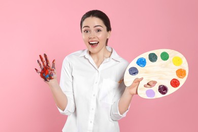 Photo of Woman with painted palm and palette on pink background. Young artist