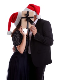 Photo of Couple covering their faces with Christmas gift on white background