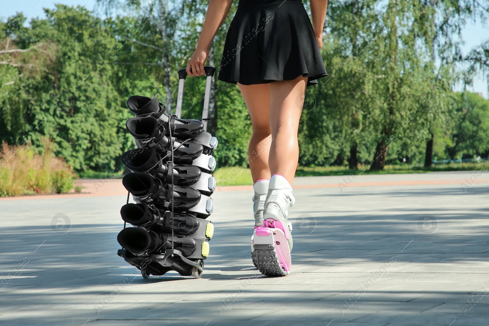 Photo of Woman with kangoo jumping boots on hand trolley outdoors, closeup