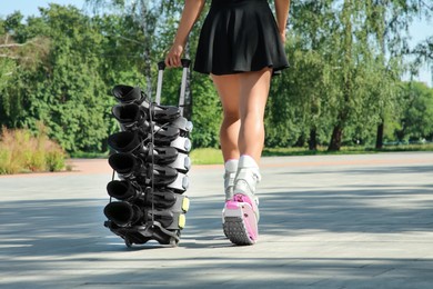 Photo of Woman with kangoo jumping boots on hand trolley outdoors, closeup