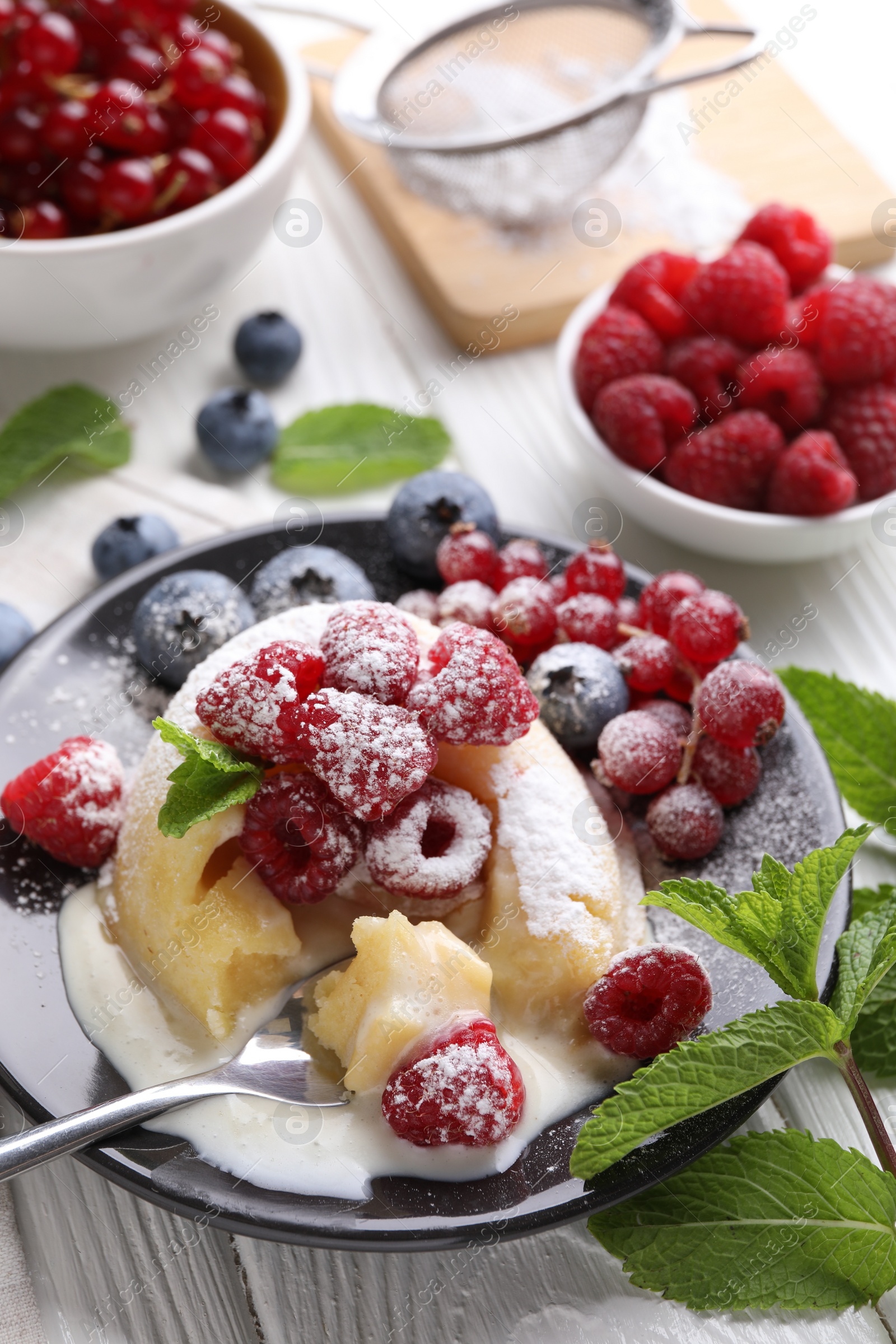 Photo of Delicious vanilla fondant served with fresh berries on white wooden table, closeup