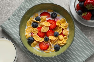 Photo of Corn flakes with berries in bowl served on grey table, flat lay