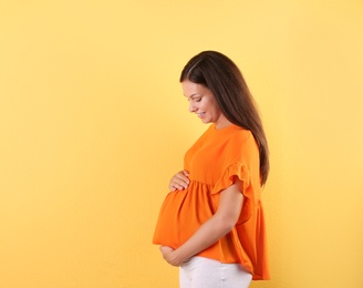 Photo of Happy pregnant woman posing on color background. Space for text