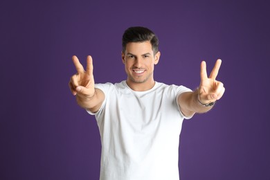 Photo of Man showing number four with his hands on purple background