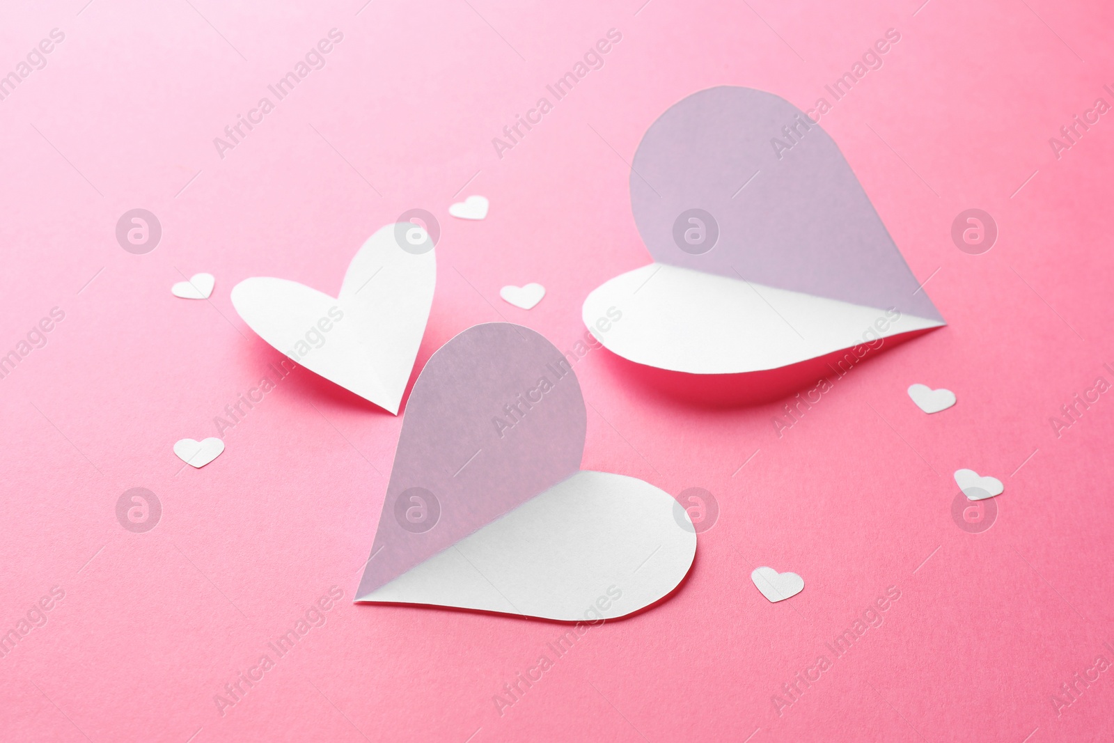 Photo of Many white paper hearts on pink background