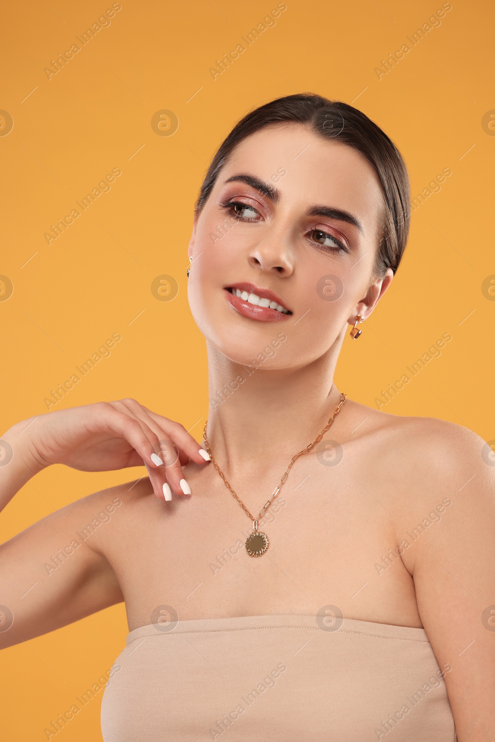 Photo of Beautiful woman with elegant jewelry on orange background