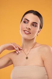 Beautiful woman with elegant jewelry on orange background