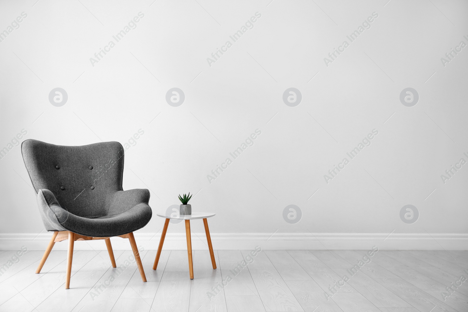 Photo of Stylish room interior with comfortable armchair near light wall, space for text