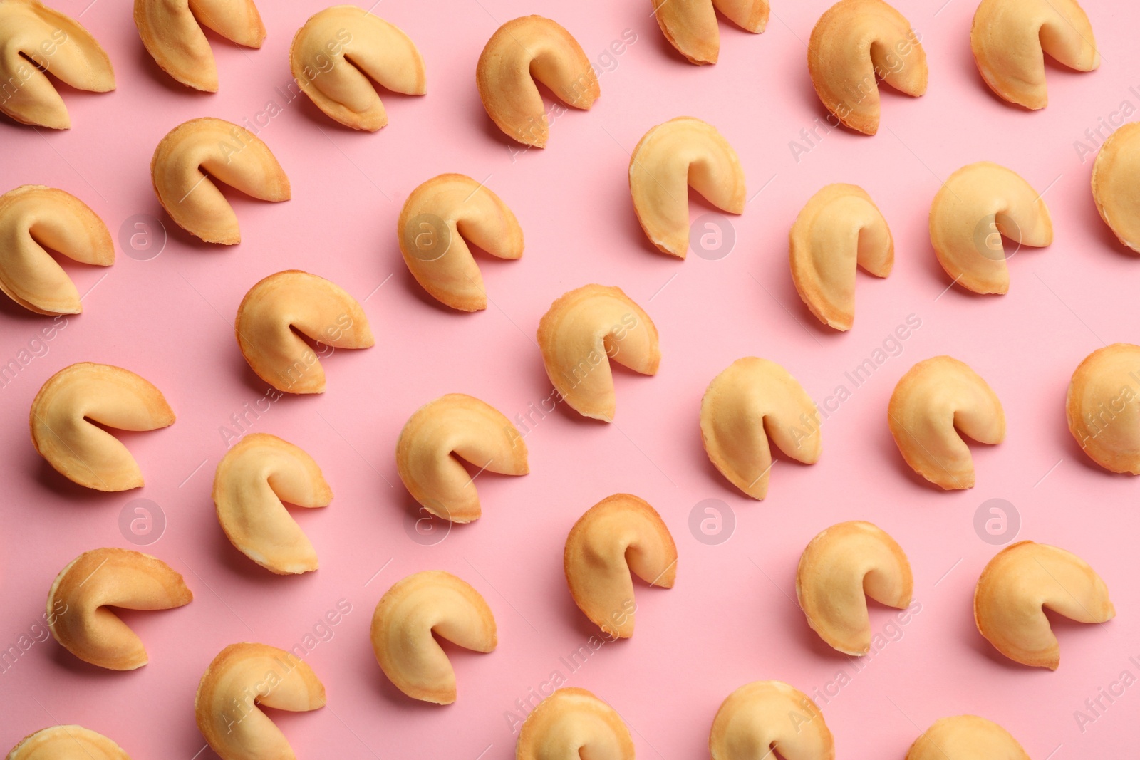 Photo of Many tasty fortune cookies with predictions on pink background, flat lay