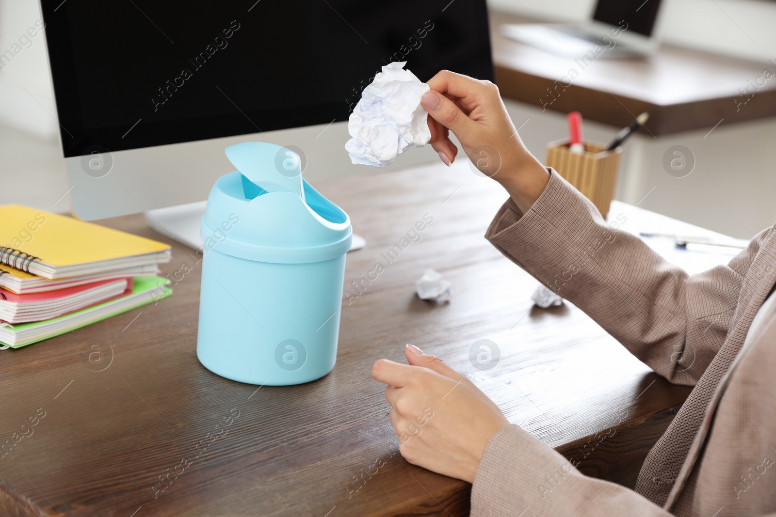 Photo of Young woman throwing paper into recycling bin at office, closeup