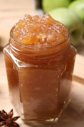 Photo of Delicious apple jam in jar on wooden table, closeup