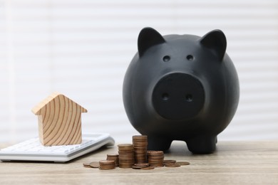 House model, calculator, piggy bank and stacked coins on wooden table