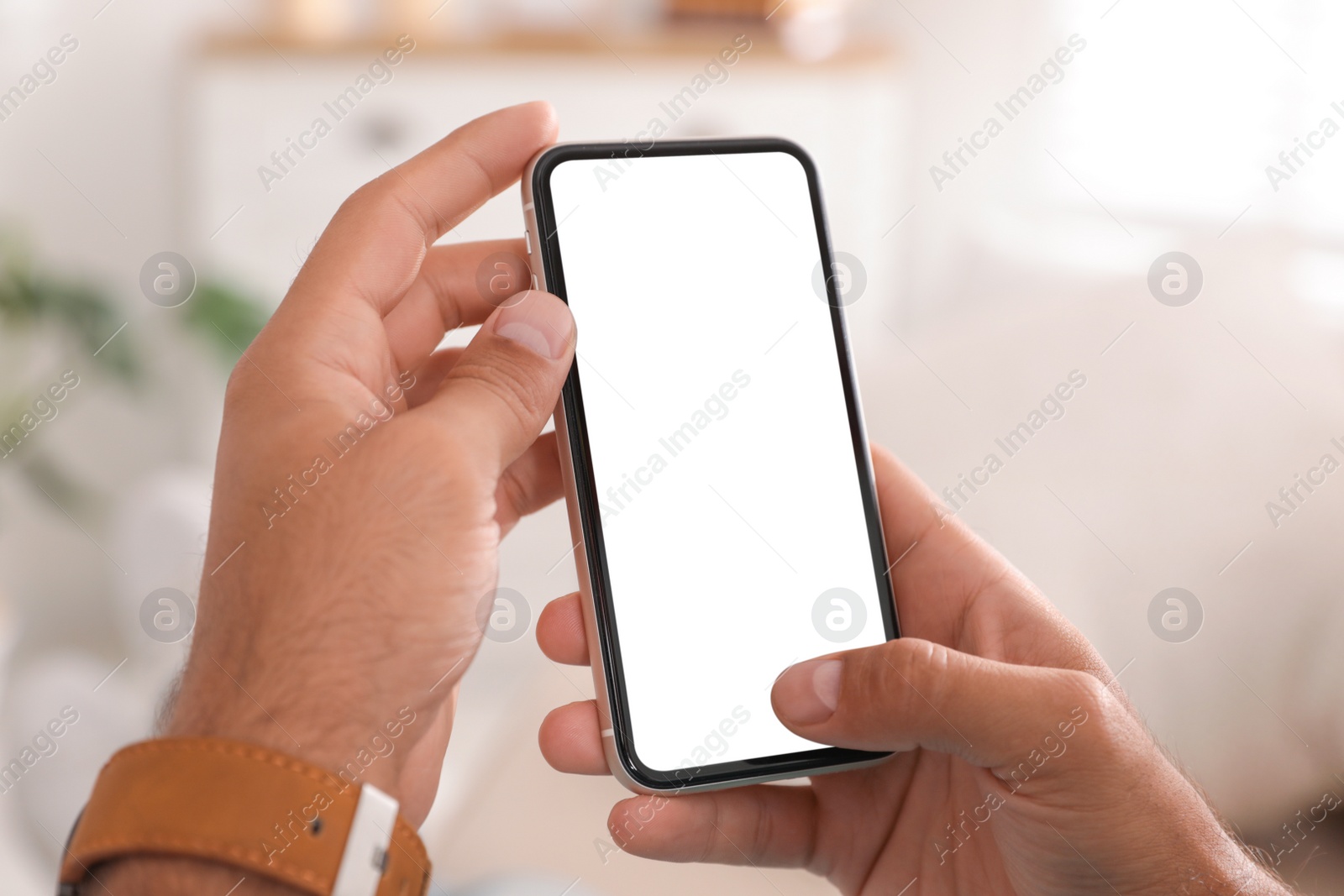 Photo of Man using mobile phone with empty screen indoors, closeup